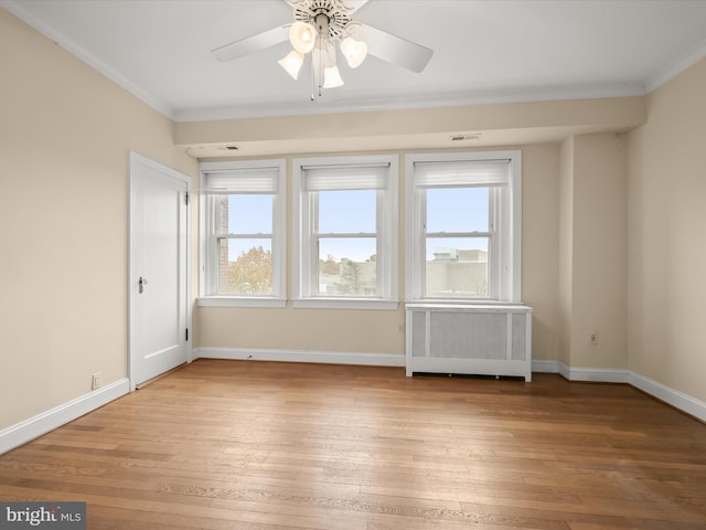 spare room with crown molding, light wood-type flooring, radiator heating unit, and baseboards