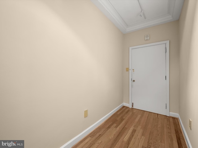 doorway to outside featuring light wood finished floors, rail lighting, baseboards, and ornamental molding