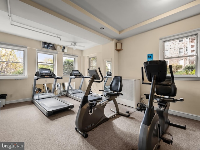 gym with a tray ceiling and baseboards