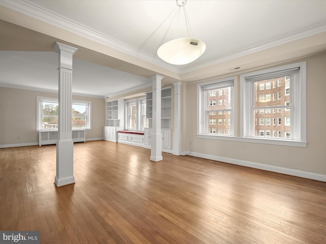 unfurnished living room featuring radiator, crown molding, baseboards, hardwood / wood-style floors, and decorative columns