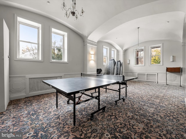 rec room featuring lofted ceiling, a notable chandelier, carpet flooring, and a decorative wall