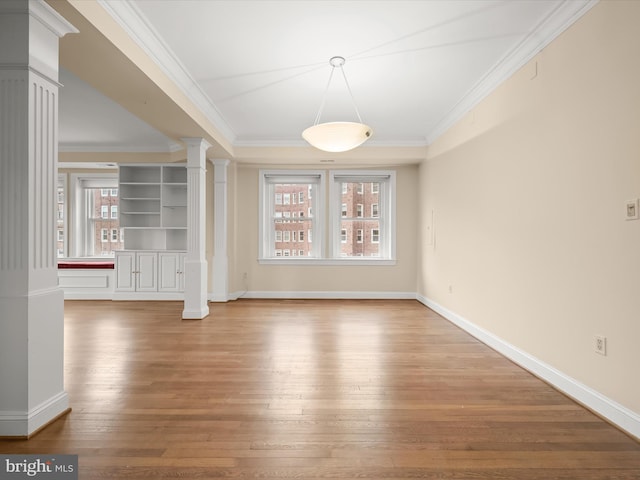 unfurnished dining area with baseboards, wood finished floors, ornamental molding, and ornate columns