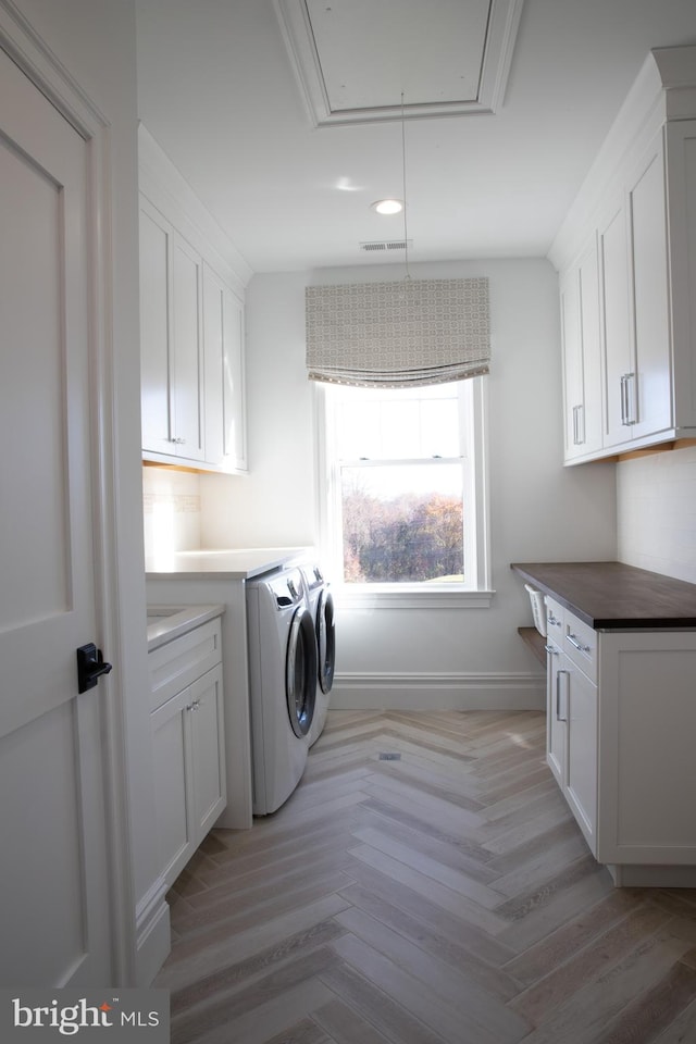 laundry room with cabinets, independent washer and dryer, and light parquet flooring