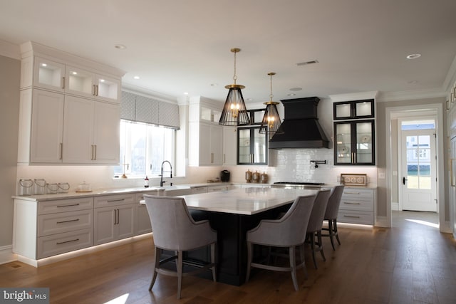 kitchen with white cabinets, a kitchen island, and custom exhaust hood