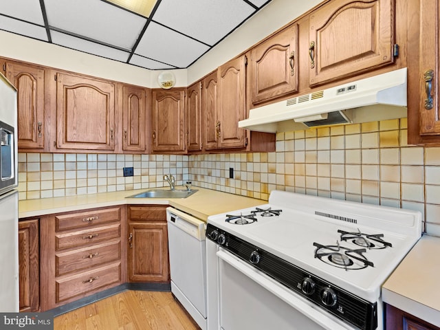 kitchen with white appliances, tasteful backsplash, sink, and light wood-type flooring