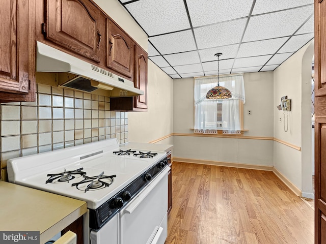 kitchen with white range with gas stovetop, decorative light fixtures, light hardwood / wood-style floors, and tasteful backsplash