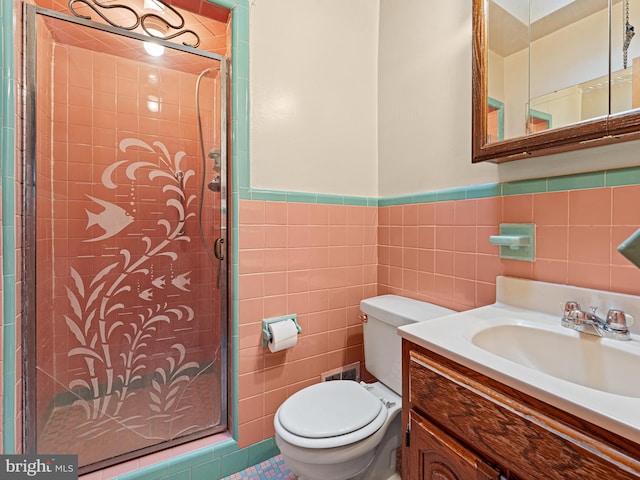 bathroom featuring a shower with shower door, toilet, tile patterned floors, tile walls, and vanity