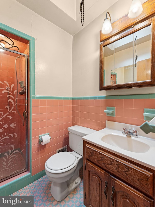 bathroom featuring vanity, toilet, walk in shower, and tile walls