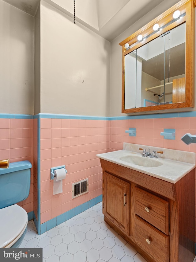 bathroom with vanity, toilet, tile patterned floors, and tile walls