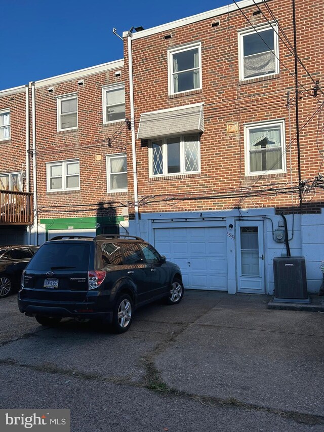 rear view of property featuring central air condition unit and a garage