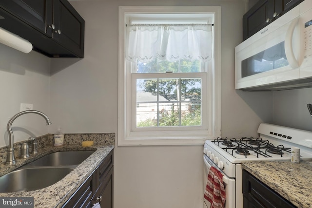 kitchen featuring white appliances, sink, and light stone counters