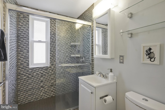 bathroom featuring walk in shower, vanity, toilet, and a healthy amount of sunlight