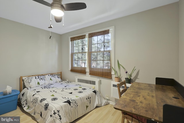 bedroom with ceiling fan, light wood-type flooring, and an AC wall unit