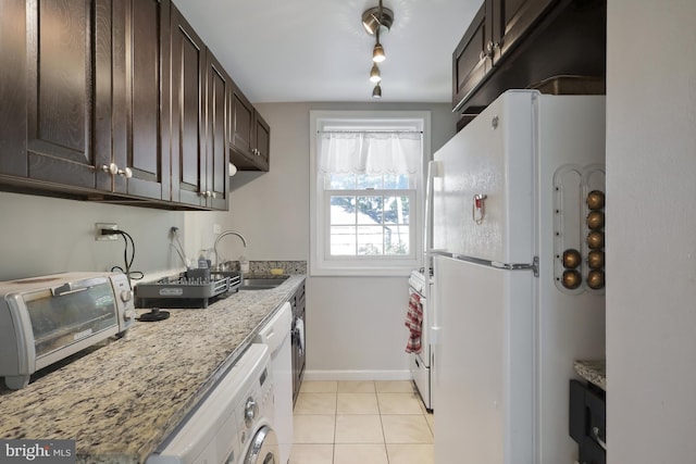 kitchen with light tile patterned floors, sink, white appliances, washer / clothes dryer, and light stone countertops