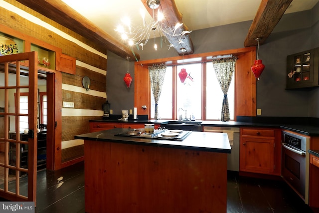 kitchen with sink, beam ceiling, a kitchen island, an inviting chandelier, and stainless steel appliances