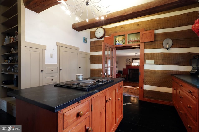 kitchen with beam ceiling, dark wood-type flooring, black gas stovetop, a center island, and an inviting chandelier