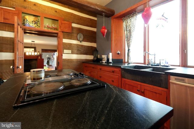 kitchen with wood walls, sink, pendant lighting, and stainless steel appliances