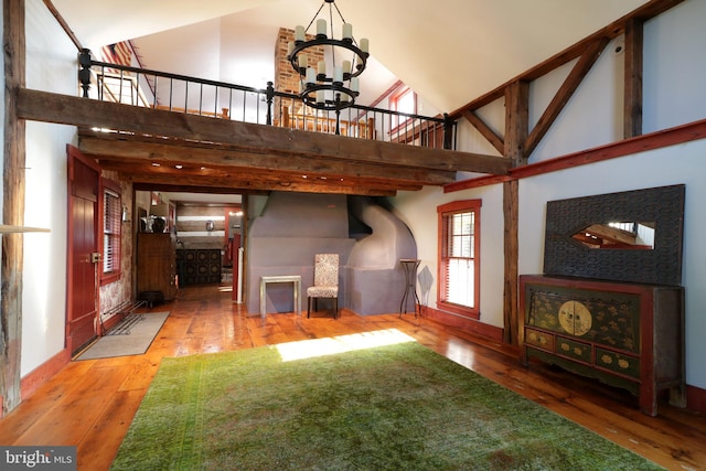 unfurnished living room with high vaulted ceiling, a notable chandelier, and hardwood / wood-style flooring