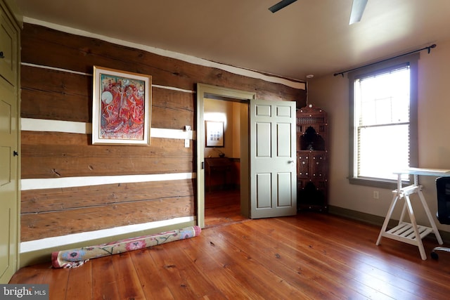 interior space with hardwood / wood-style flooring and wooden walls