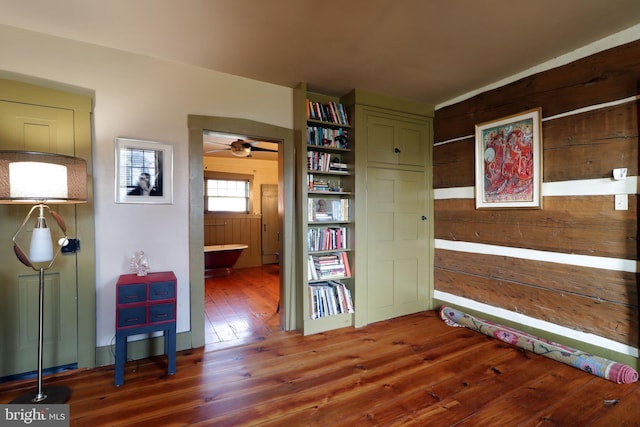 interior space featuring wood walls, dark hardwood / wood-style flooring, and ceiling fan