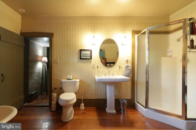 bathroom with walk in shower, toilet, and hardwood / wood-style floors