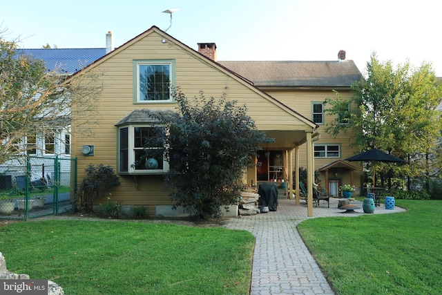 back of property with a lawn and a patio area