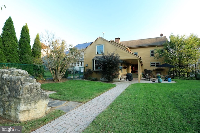 rear view of house with a lawn and a patio