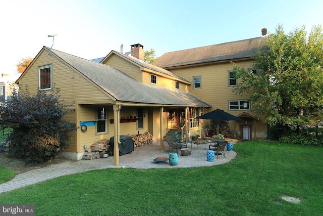 rear view of house featuring a lawn and a patio