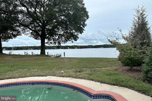 view of pool with a water view and a yard