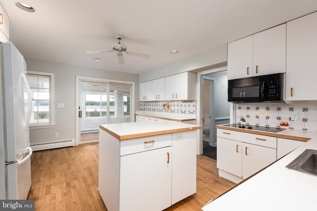 kitchen with white cabinets, a baseboard radiator, light hardwood / wood-style floors, and black appliances