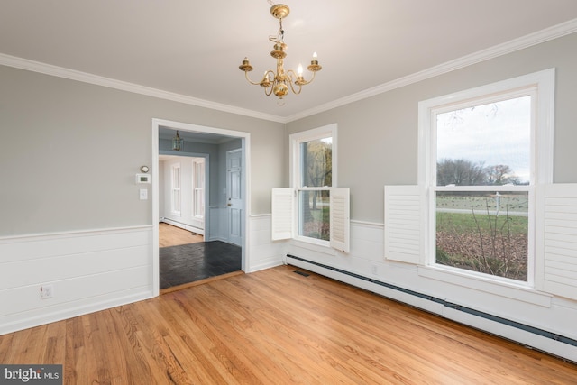 spare room featuring hardwood / wood-style floors, plenty of natural light, an inviting chandelier, and a baseboard radiator