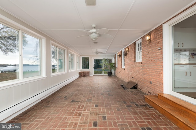 unfurnished sunroom featuring a baseboard radiator, ceiling fan, and a water view