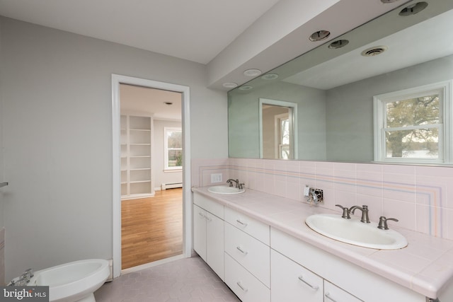 bathroom featuring vanity, backsplash, a baseboard radiator, and tile patterned floors