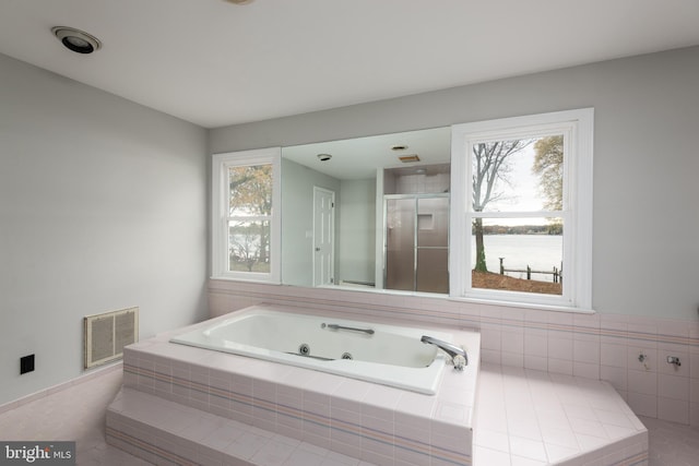 bathroom featuring tiled bath, tile patterned floors, and plenty of natural light