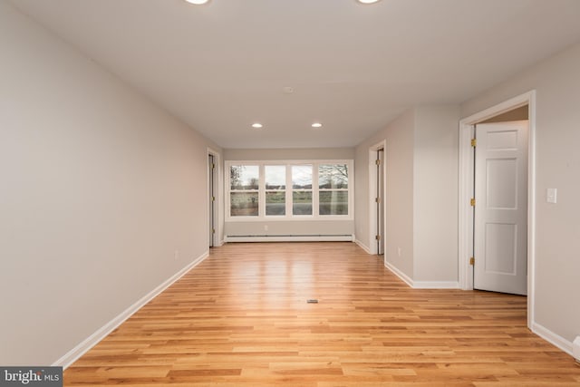 unfurnished room with baseboard heating and light wood-type flooring