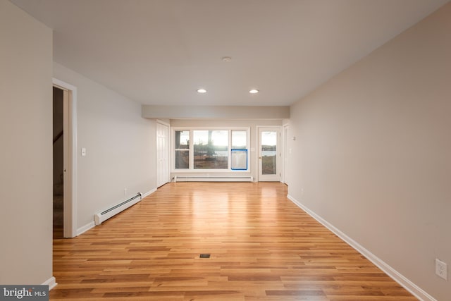 empty room with a baseboard heating unit and light hardwood / wood-style flooring