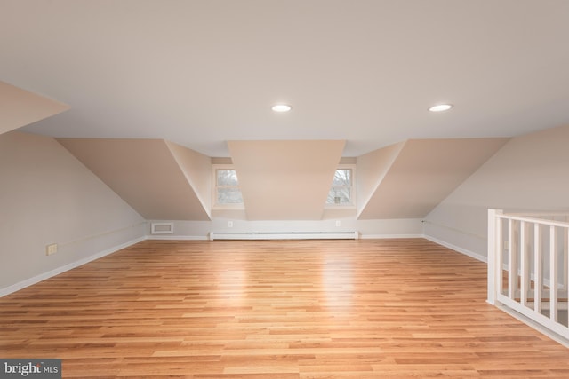 additional living space featuring a baseboard radiator, lofted ceiling, and light hardwood / wood-style flooring