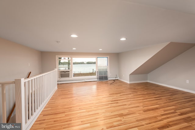 additional living space featuring cooling unit, light wood-type flooring, and a baseboard radiator