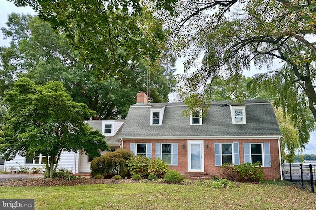 cape cod home featuring a front yard