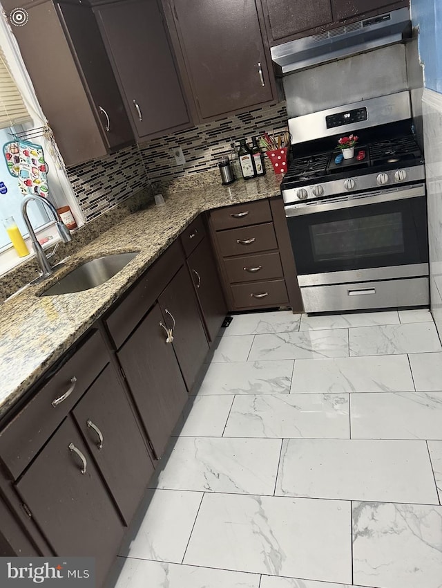 kitchen featuring decorative backsplash, extractor fan, appliances with stainless steel finishes, sink, and light stone counters