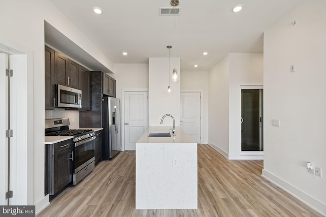 kitchen with sink, pendant lighting, light hardwood / wood-style flooring, and stainless steel appliances