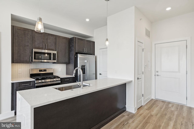 kitchen featuring appliances with stainless steel finishes, sink, dark brown cabinetry, pendant lighting, and light hardwood / wood-style flooring