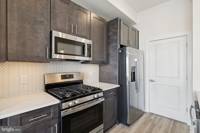 kitchen with backsplash, stainless steel appliances, dark brown cabinets, and light hardwood / wood-style flooring