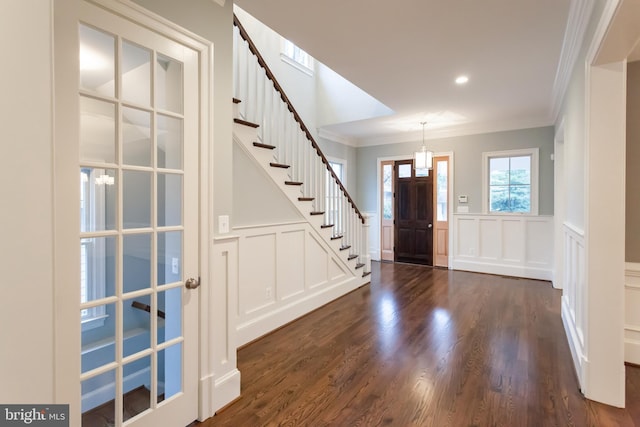 entrance foyer with dark hardwood / wood-style flooring, an inviting chandelier, and crown molding