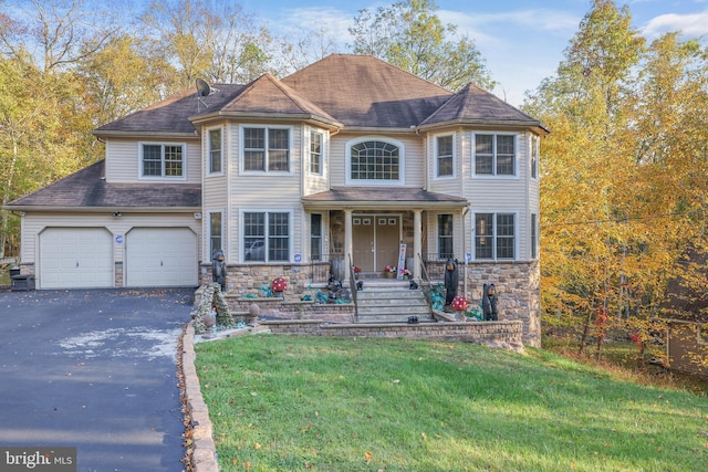 view of front of house featuring a garage, a porch, and a front lawn