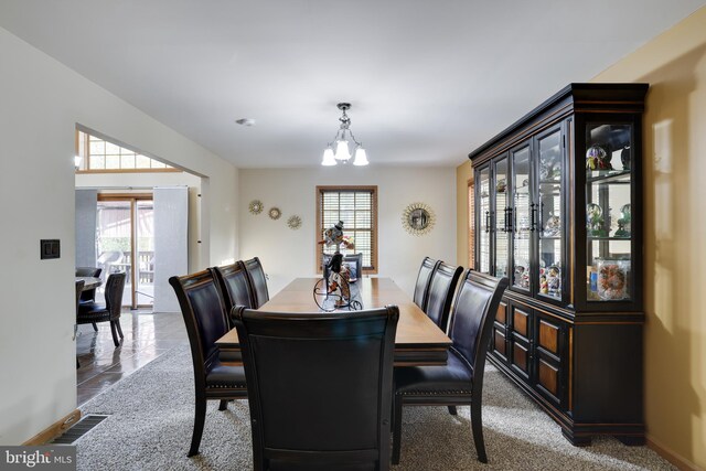 carpeted dining room with an inviting chandelier