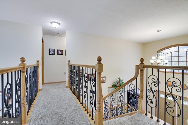 hallway with a notable chandelier and carpet