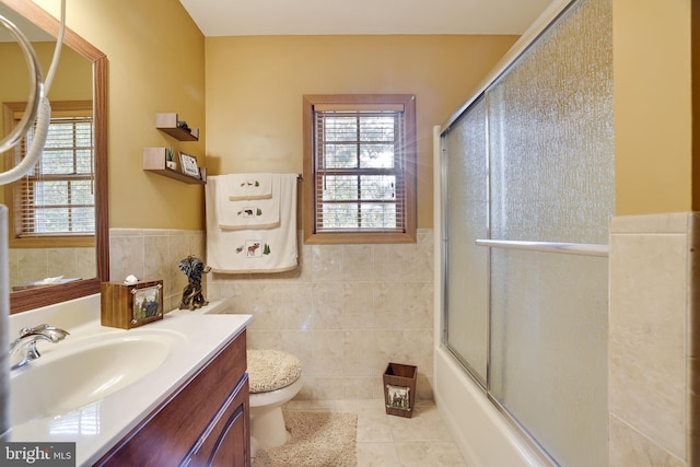 full bathroom with vanity, toilet, bath / shower combo with glass door, tile walls, and tile patterned flooring