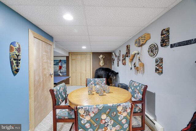 carpeted dining room featuring a baseboard radiator and a paneled ceiling