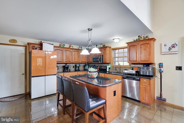 kitchen with a breakfast bar, hanging light fixtures, a kitchen island, decorative backsplash, and appliances with stainless steel finishes